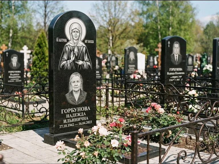Памятник с гравировкой иконы: стела с арочным верхом и киотом под образ — гравировка образа Матроны Московской, гранитный цоколь с тёмной плиткой, работа «Ковалёв» в Рязани