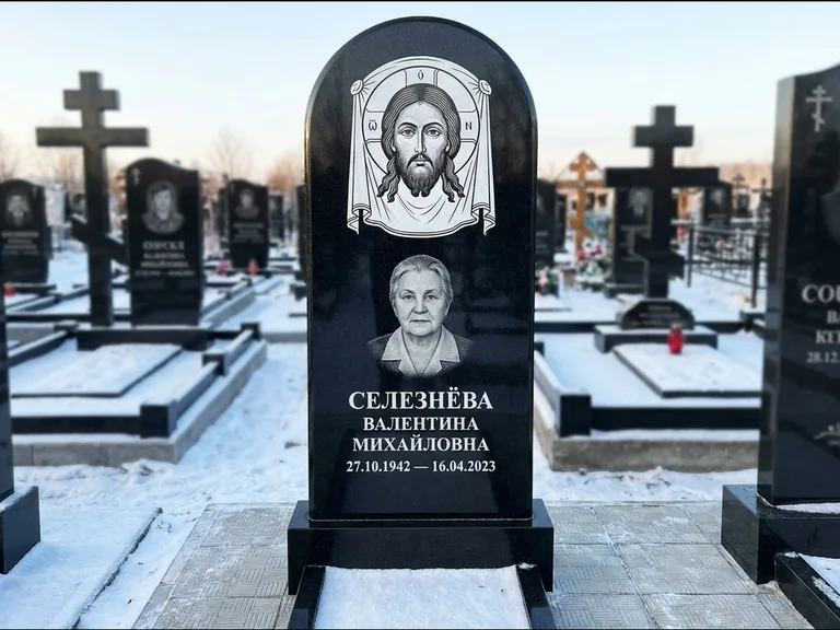 Памятник с гравировкой иконы: небольшая скромная одиночная стела с именной иконой — золочёный нимб на образе, аккуратный участок с газоном, работа «Ковалёв» в Рязани