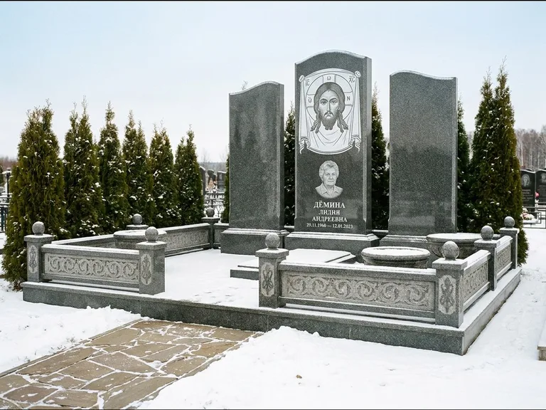 Памятник с гравировкой иконы: узкая вертикальная стела-пилон с ликом — икона в резной рамке-киоте, открытая лужайка без ограды, работа «Одинцов» в Рязани