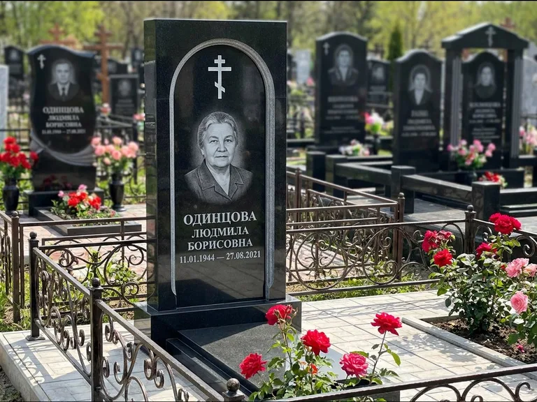 Памятник из чёрного гранита — скромная невысокая стела с крестом с терновым венцом, работа «Лаврентьева» в Рязани